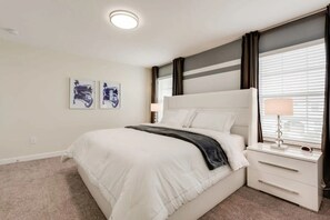 Ein Schlafzimmer mit einem großen Bett, einem Nachttisch mit Lampe und zwei an der Wand befestigten Kunstwerken.
