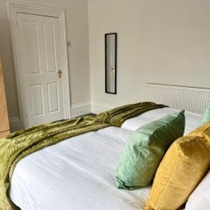 A bedroom with a bed, pillows, a door, and a radiator. - Sunderland - Apartment - Stay 4 - Central Location (Sunderland)