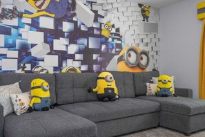 A grey sectional sofa with three minion plush toys and matching pillows. - Storey Lake 6BR Villa 10 min to Disney (Kissimmee)