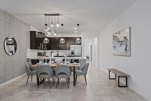 A modern kitchen with dark wooden cabinets, a central island, and pendant lighting. - Cozy 3BR in Champions Gate With Amazing Views! (Davenport)
