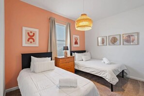 A hotel room with two beds, a nightstand, a lamp, and framed artwork on the walls. - Cozy 3BR in Champions Gate With Amazing Views! (Davenport)