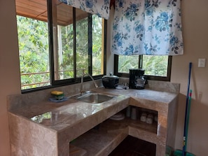 A kitchen with a marble countertop, a sink, a coffee maker, and a window with a view of greenery. - Cozy 2-bedroom cabin in nature full Puerto Viejo, Limon, Costa Rica (Limón)