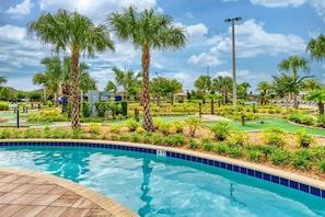 A pool area with a golf course, palm trees, and a clear sky. - Cozy 3BR in Storey Lake 10 Min From Disney! (Kissimmee)