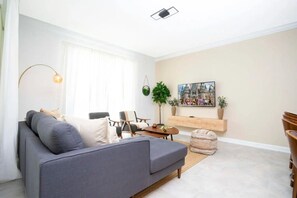 A living room with a grey sofa, a coffee table, and a TV mounted on the wall. - Luxury 4BR Home w/ Pool Near Disney! (Davenport)