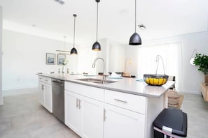Een moderne keuken met witte kasten, een roestvrijstalen spoelbak en hanglampen.