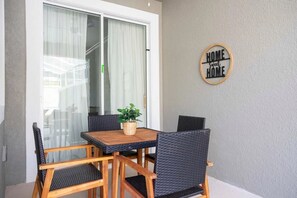 A dining area with a table and four chairs, a potted plant, and a sign on the wall. - Luxury 4BR Home w/ Pool Near Disney! (Davenport)