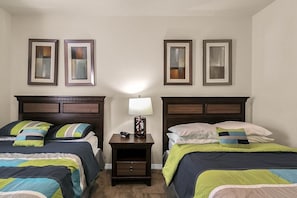 A bedroom with two beds, a nightstand with a lamp, and framed artwork on the walls. - 3BR Lucaya Village Home, Sleeps 8 (Kissimmee)