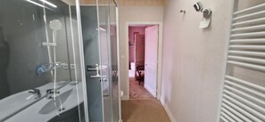 A bathroom with a glass shower enclosure, a toilet, and a towel rack.