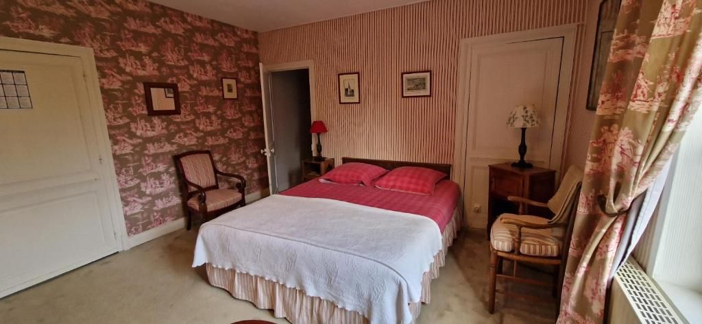 A bedroom with a bed, a chair, a nightstand, and a door.