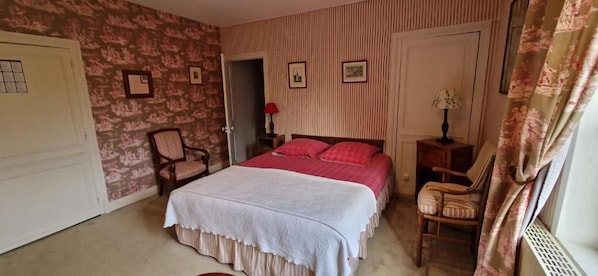A bedroom with a bed, a chair, a nightstand, and a door.