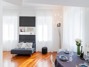 A modern room with a bed, a dining table set for two, and a tall floor lamp. - Italianway Easy - Cavallotti 17 (Milan)