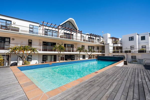 A modern hotel with a swimming pool, wooden deck, and balconies with railings. - Azure 119 (Cape Town)