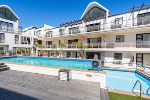 A modern hotel with a pool area, multiple balconies, and a clear blue sky. - Azure 119 (Cape Town)