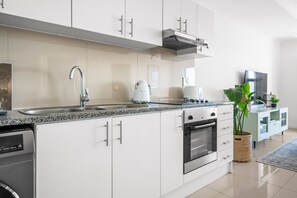 A modern kitchen with stainless steel appliances, a built-in oven, and a coffee maker. - Azure 119 (Cape Town)
