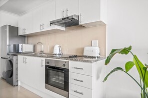 A modern kitchen with white cabinetry, a built-in oven, a microwave, and a toaster. - Azure 119 (Cape Town)