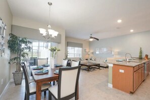 A spacious kitchen with a dining area, a living room, and a ceiling fan. - Family-friendly 4BR Townhome With Private Pool (Kissimmee)