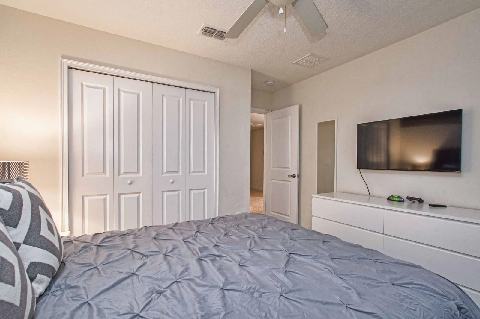 Un dormitorio con cama, televisor, cómoda y armario.