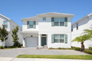 A two-story residential building with a white exterior, a garage, and a front entrance. - 6BR Home Private Pool 10 Min to Disney! (Kissimmee)