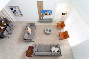 A modern living room with a gray sofa, two armchairs, a coffee table, and a TV on a stand. - 5BR Villa w/ Pool & Disney Themes (Kissimmee)
