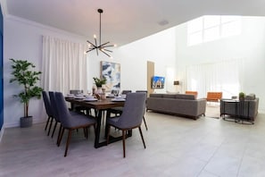 Un grand salon comprenant une table à manger pour quatre personnes, un canapé et un téléviseur.