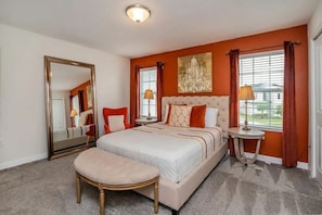 A hotel room with a large bed, a sitting area with a chair, a round table, and a large mirror. - 4BR Home w/ Heated Pool Storey Lake (Kissimmee)