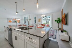 A modern kitchen with a central island, stainless steel appliances, and pendant lighting. - Luxury & Magic: Pool Home at Storey Lake! (Kissimmee)