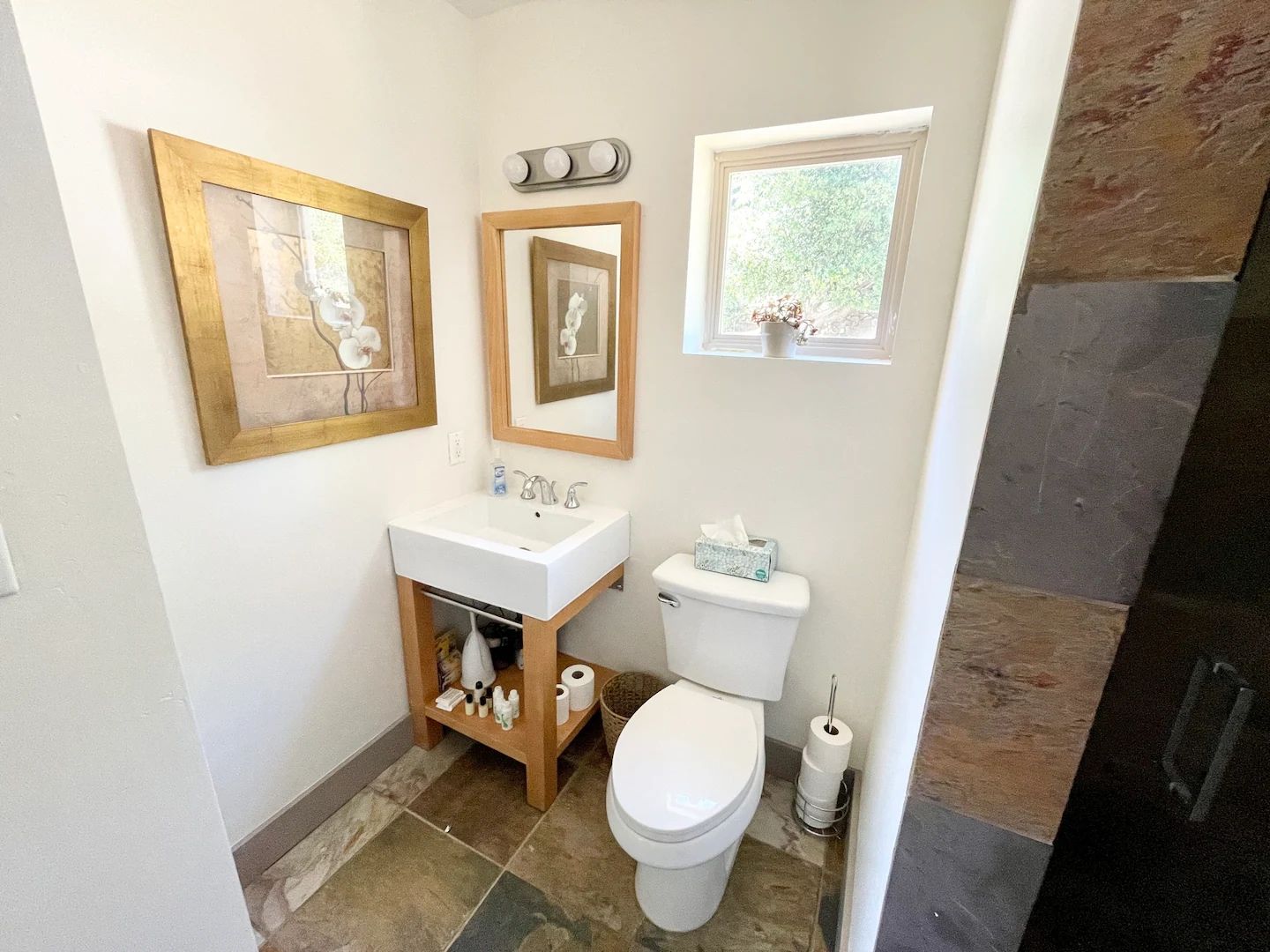 A bathroom with a white sink, a toilet, and two framed pictures on the wall.