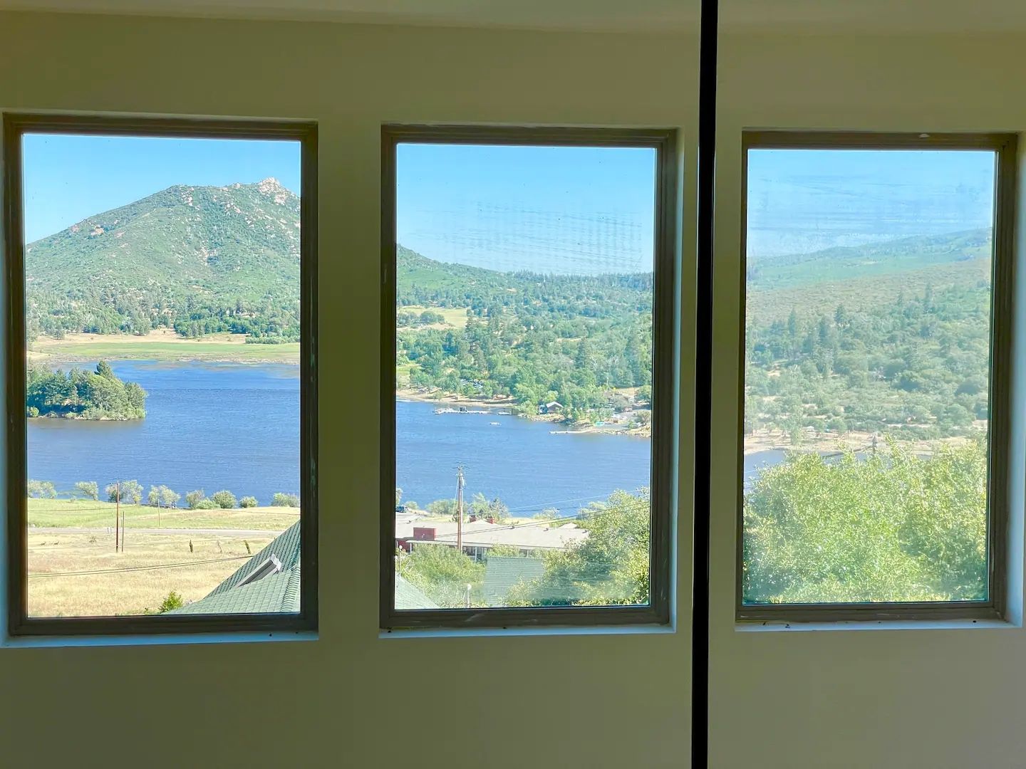 Three windows with a view of a lake, forest, and distant hills.