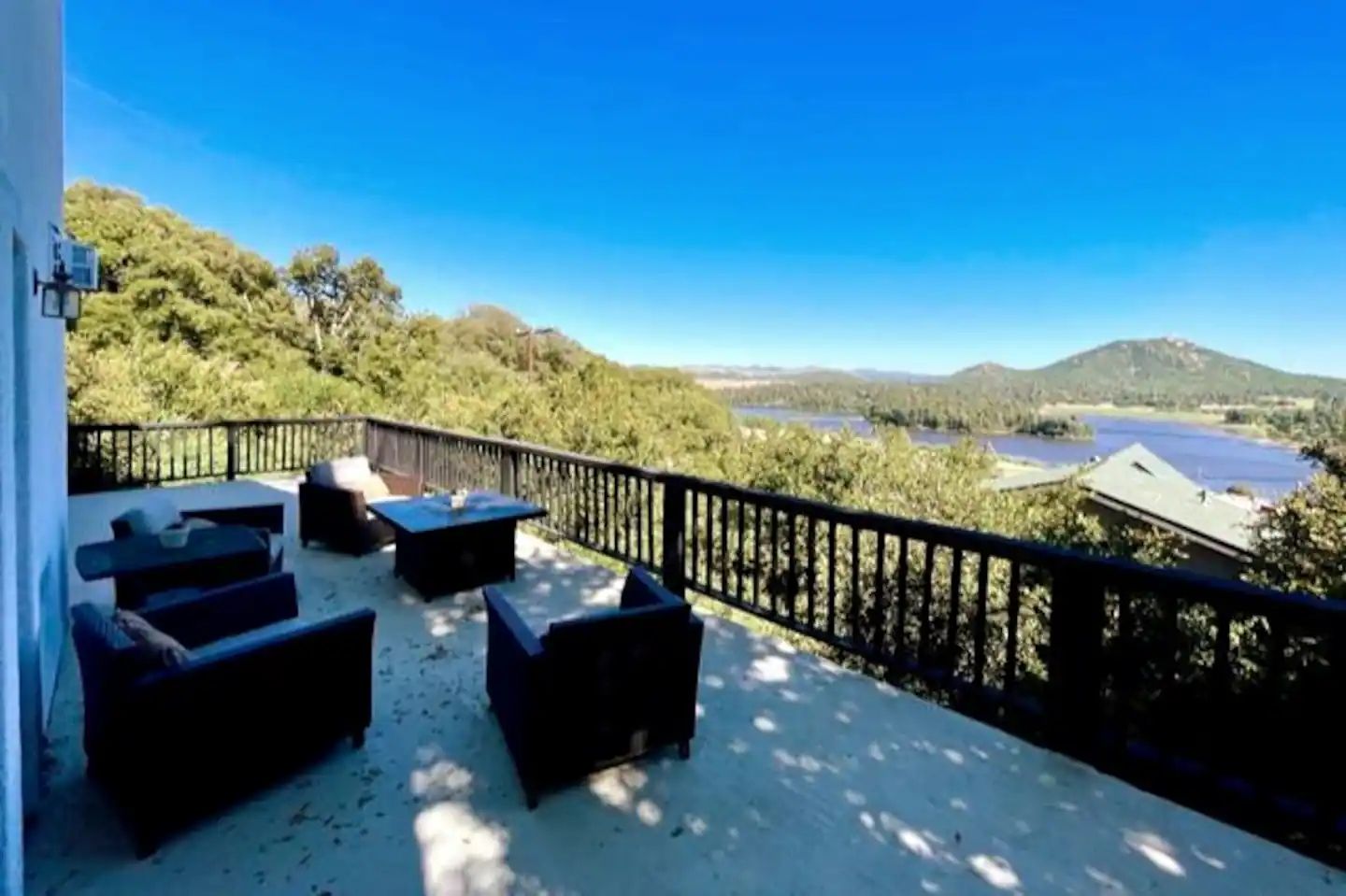 A balcony with outdoor furniture and a view of a lake and mountains.