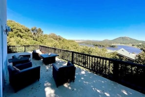 Un balcón con mobiliario exterior y vista a un lago y montañas.