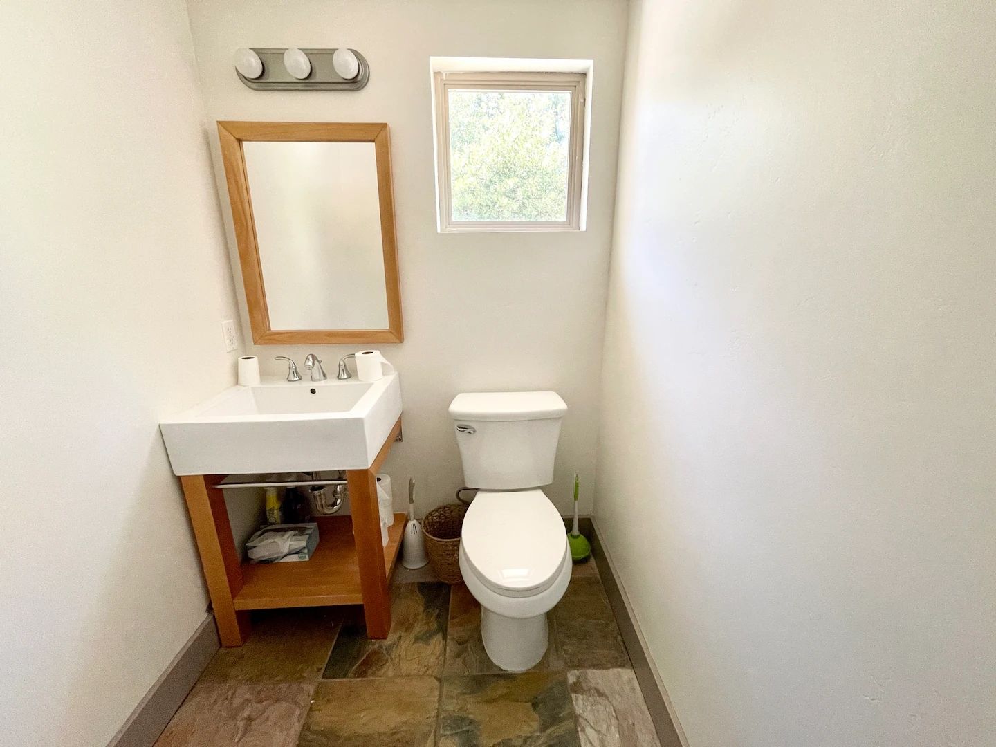Een badkamer met een wit wastafel, een toilet, een spiegel en een raam.