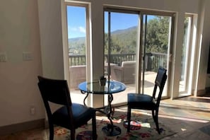 Ein Zimmer mit Glastür und Zugang zu einem Balkon mit Blick auf eine gebirgige Landschaft.