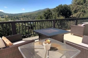 Un balcón con mobiliario de mimbre, una mesa y una planta en maceta.