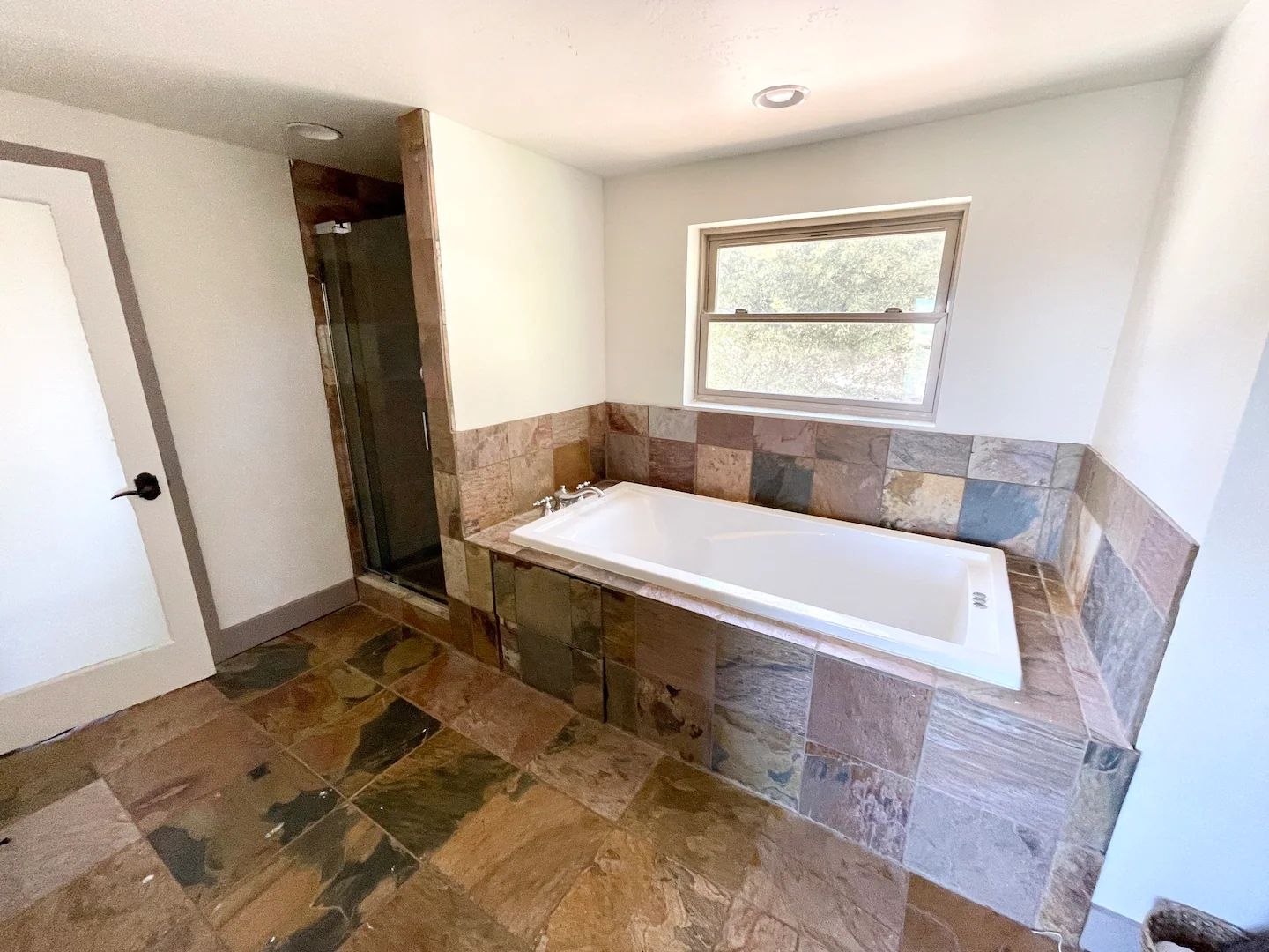 A bathroom with a walk-in shower, a bathtub, and a window.