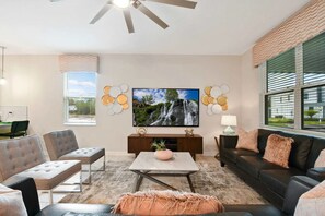 Een ruime woonkamer met een grote flatscreen-tv, comfortabele zithoek, een salontafel en een open haard.