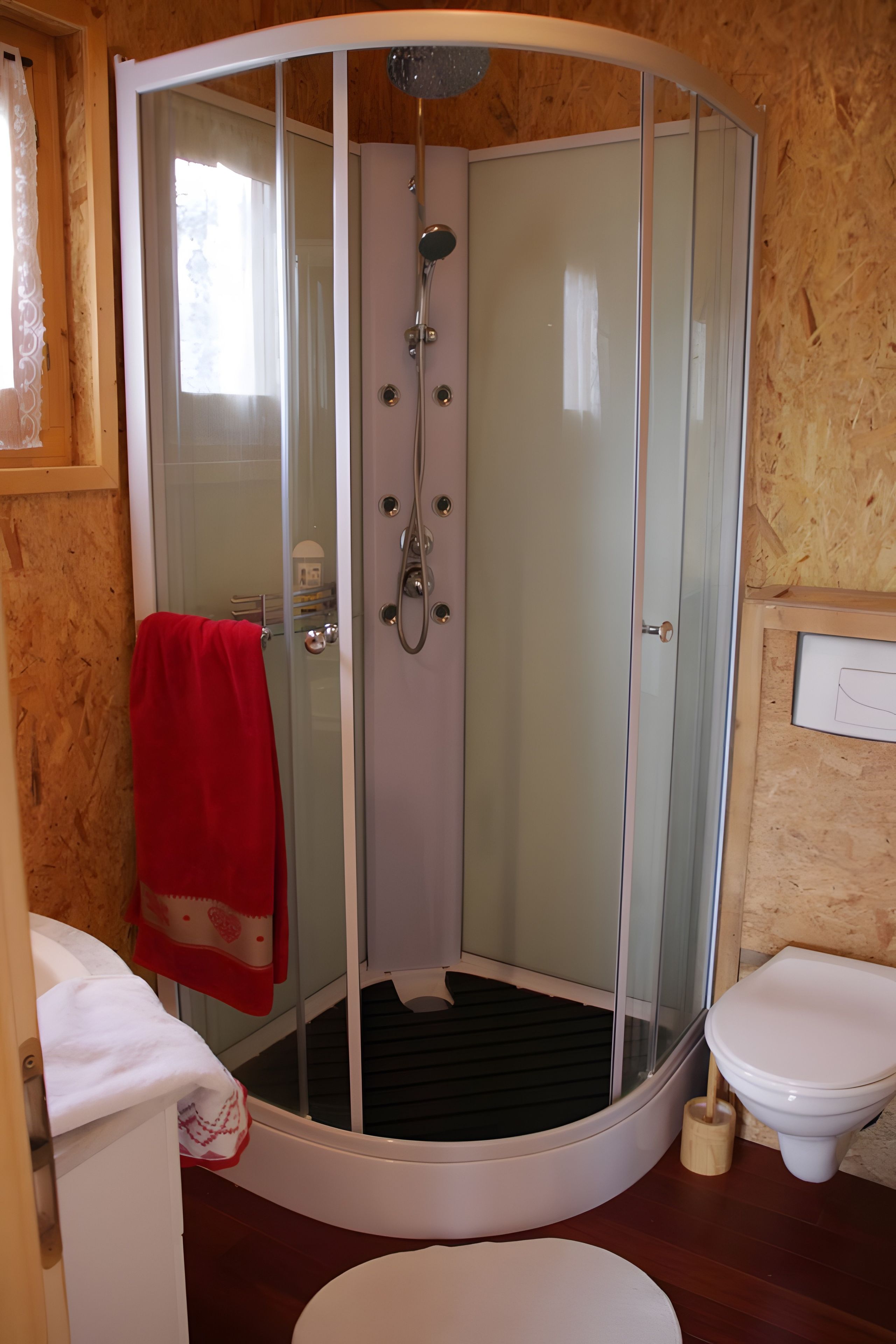 A bathroom with a glass-enclosed shower, a toilet, and a sink.