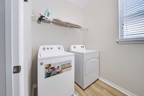 A laundry room with a front-loading washer and dryer, a drying rack, and a window with blinds. - 7BR house sleeps 20 with private pool (Kissimmee)