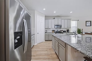 A modern kitchen with stainless steel appliances, white cabinetry, and a granite countertop. - 7BR house sleeps 20 with private pool (Kissimmee)