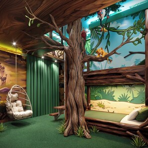 Habitació amb un arbre gran, una cadira penjant, un sofà i un mural amb una escena de savana.