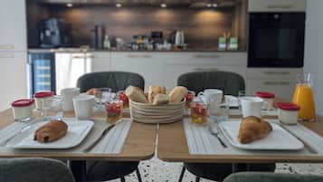 A breakfast setting with a table set for two, featuring croissants, fruit, and beverages.