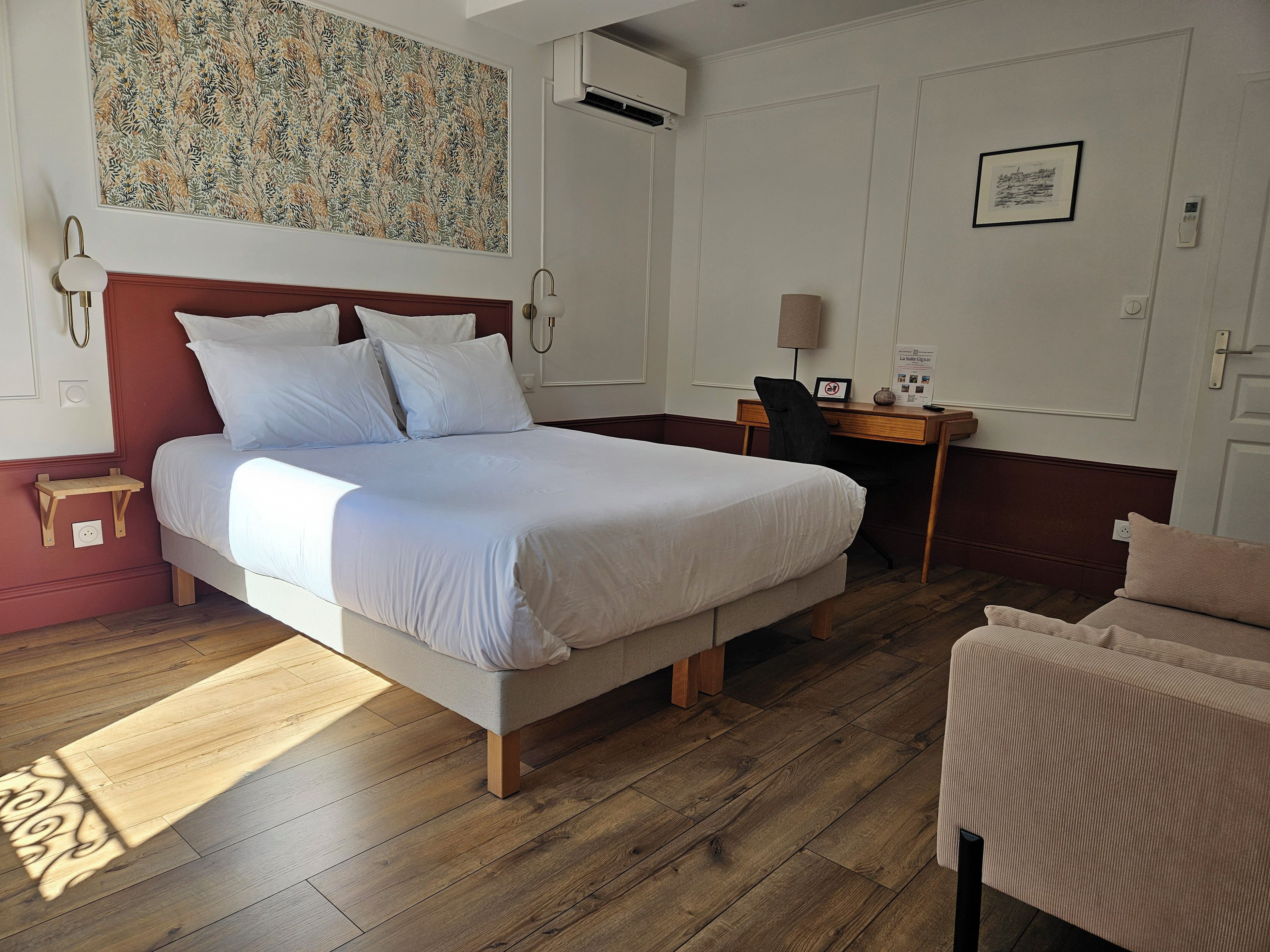 A hotel room with a large bed, a desk, a chair, and a small table.