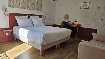 A hotel room with a large bed, a desk, a chair, and a small table.