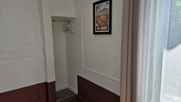 A hallway with a door, a coat rack, and a framed picture on the wall.