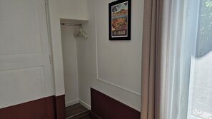 Un passadís amb una porta, una perxa i un quadre al mur.