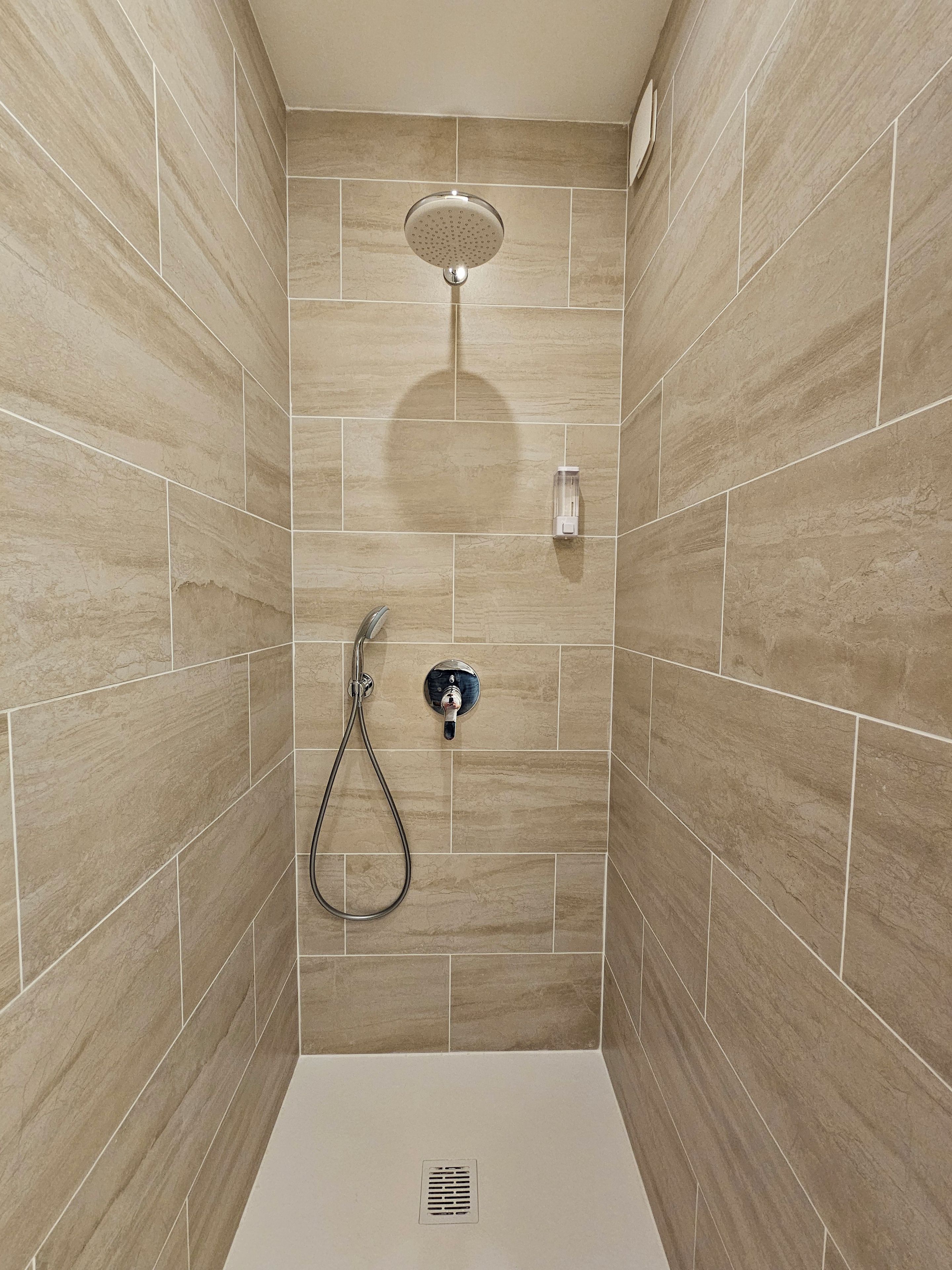 Een douche met een handdouche en een wandmengkraan.