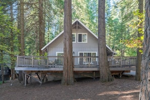 A cabin with a deck, surrounded by tall trees. - Sleeps 12 | 3 Baths | Hot Tub | Near Bear Valley (Arnold)