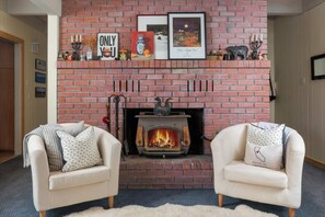 A living room with a brick fireplace, two armchairs, and a rug. - Sleeps 12 | 3 Baths | Hot Tub | Near Bear Valley (Arnold)