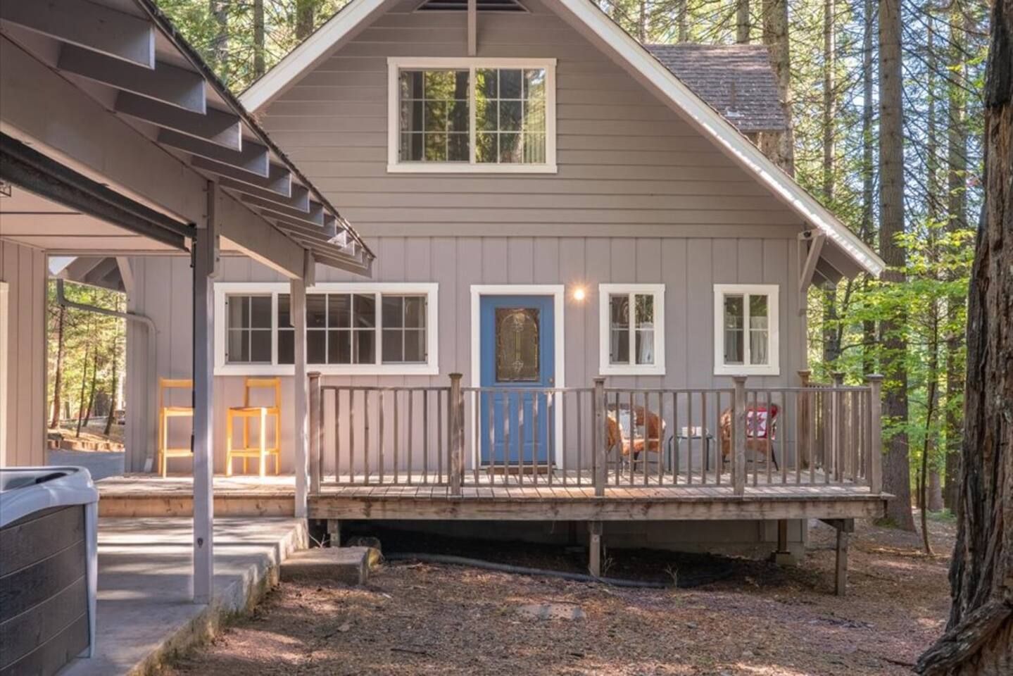 A two-story house with a covered porch, a blue door, and a fenced deck area.