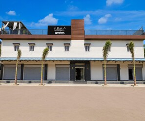 A two-story building with a sign for 'Café' and 'OYO-Serviced' on the roof. - Deluxe Room Hotel Shreeda (Greater Noida)