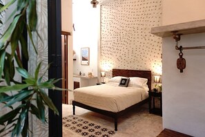 A bedroom with a bed, bedside tables, a wall-mounted light fixture, and a patterned rug. - 3-bedroom house with hacienda-inspired kitchen in charming Centro with AC (Centro)